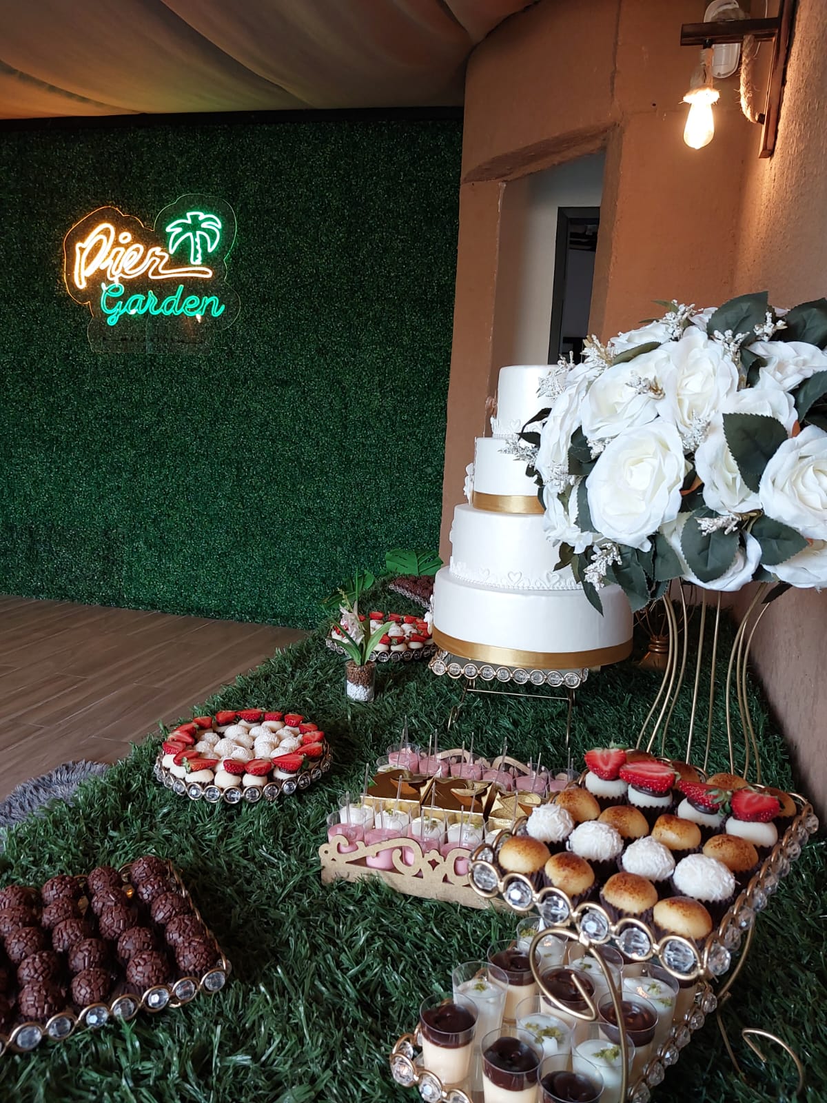 Mesa de doces com bolo de casamento e neon Pier Garden