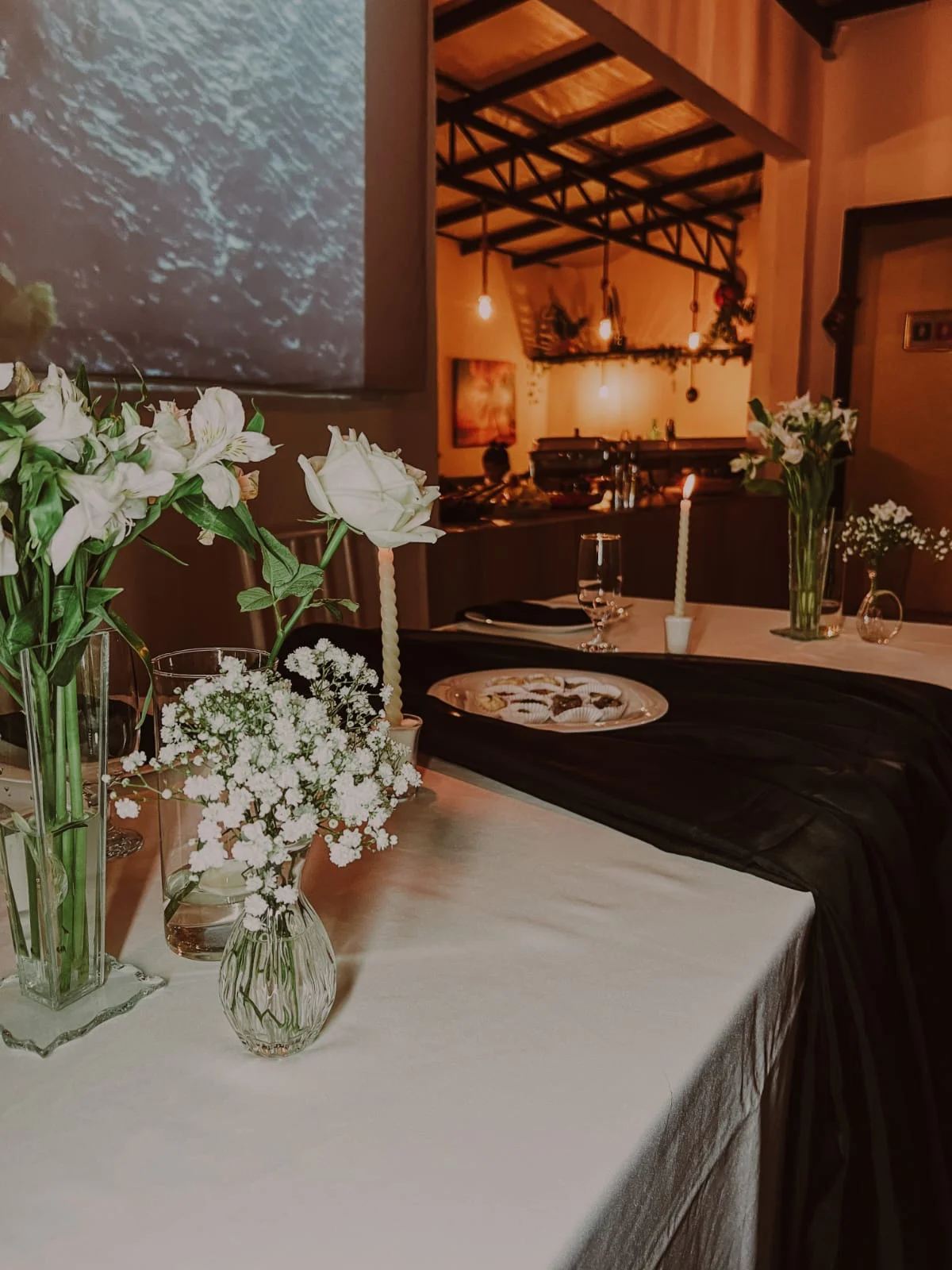 Mesa de casamento decorada com flores brancas, velas e doces